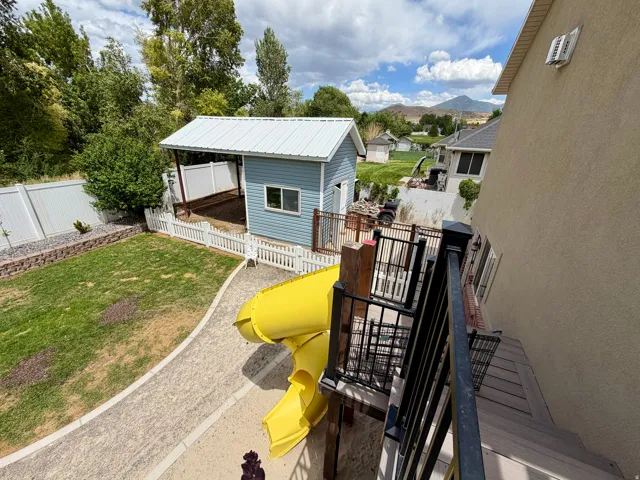 Expansive backyard featuring a manicured lawn, paved pathway, and a detached shed with a metal roof