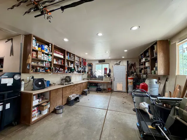 Spacious workshop featuring abundant built-in cabinetry, recessed lighting, concrete flooring, and multiple windows providing natural light