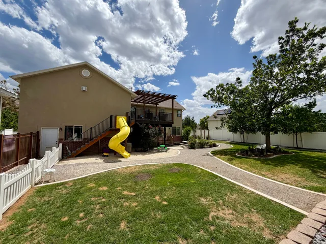 Expansive backyard featuring a manicured lawn, established shade tree, and curved gravel pathways