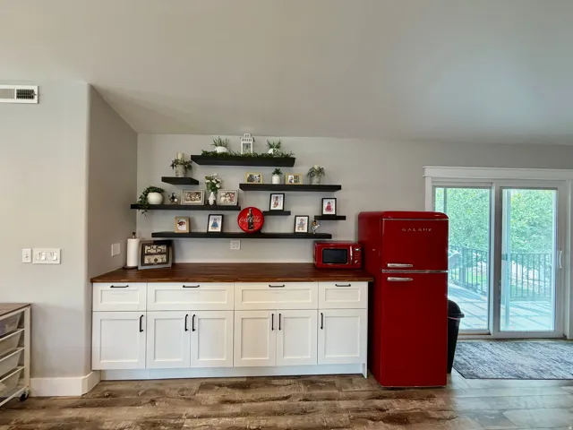 Built-in white cabinetry with black hardware, wood-finish countertop, and integrated floating shelving