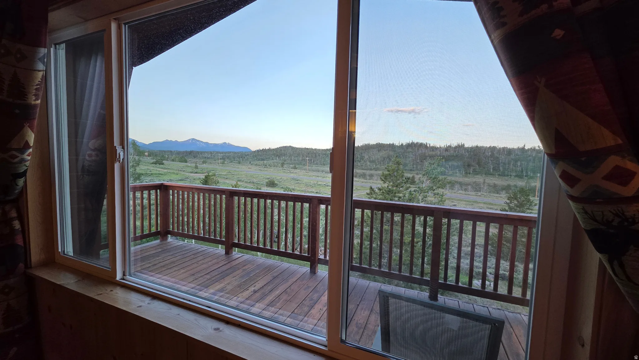 Sliding glass doors open to a spacious wooden deck with a spindle railing