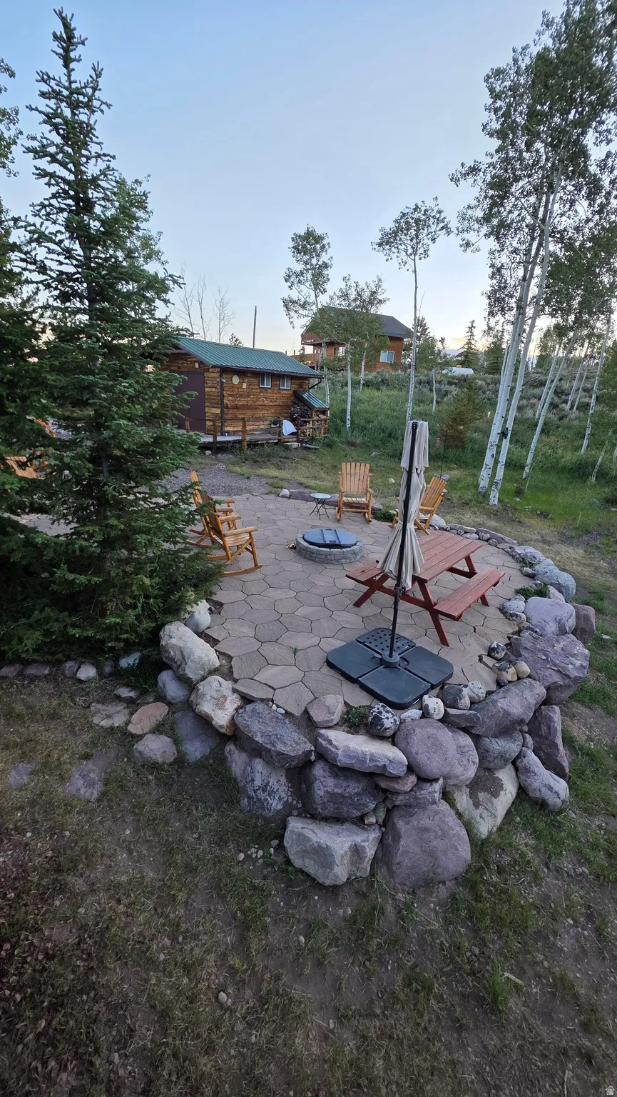 Paved patio area featuring a stone fire pit and a stone retaining wall