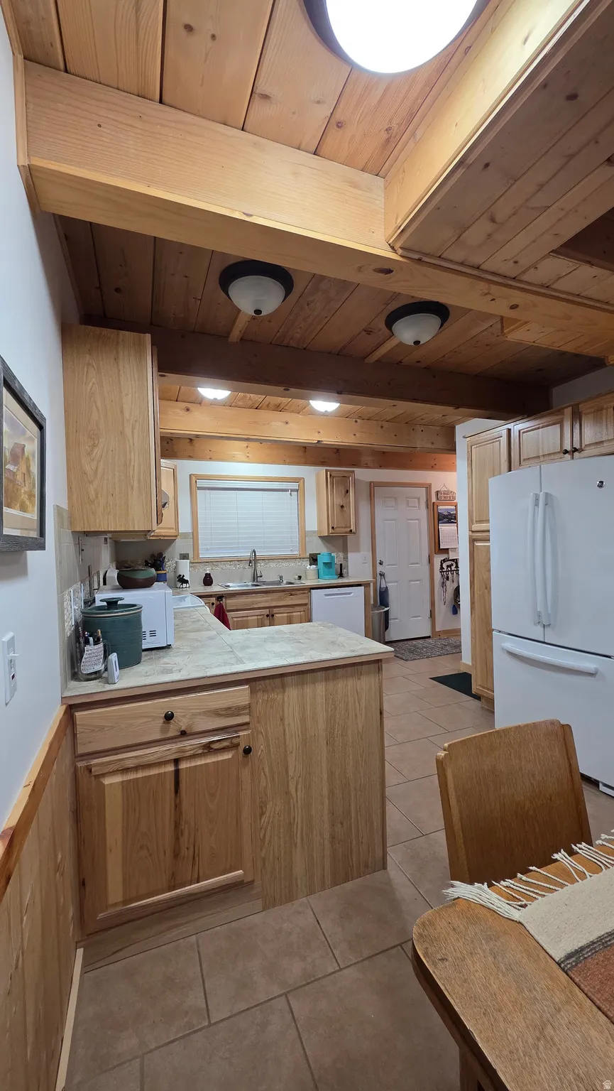 Kitchen featuring exposed wood beam ceilings and wood-paneled walls