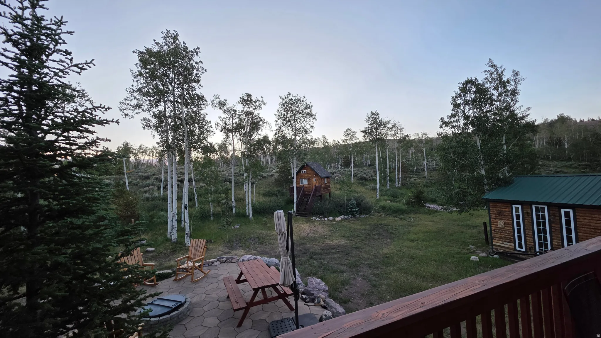 Expansive outdoor patio featuring flagstone pavers, a built-in fire pit, and a wooden deck railing