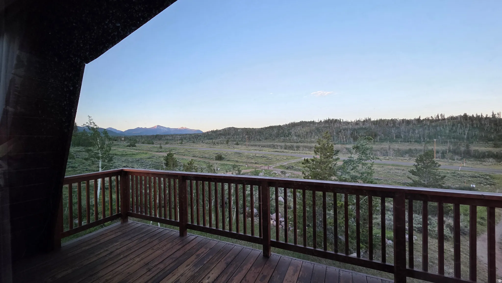 Expansive outdoor deck featuring wood-finish flooring and a wood railing