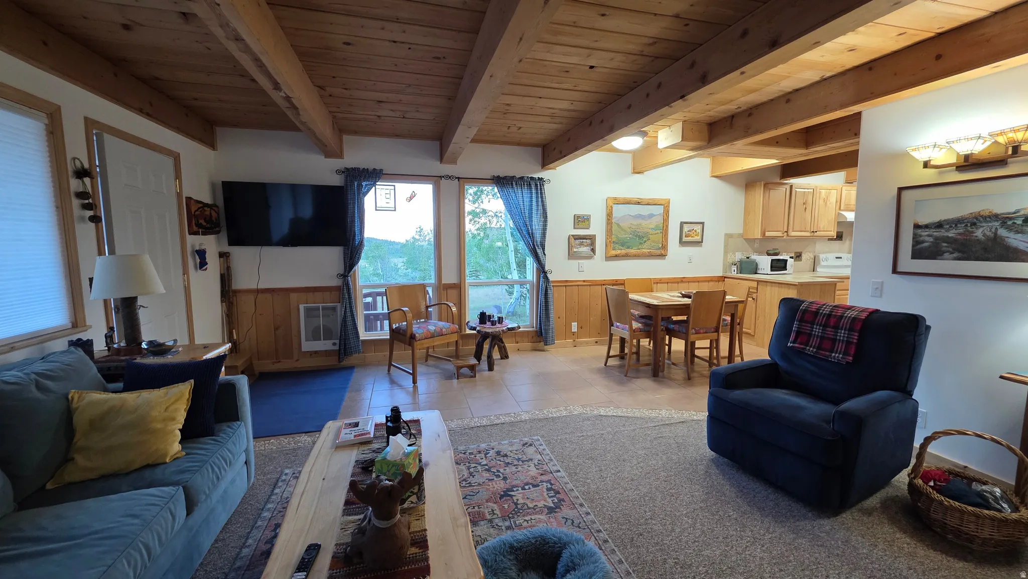 Exposed wood beam ceiling in an open concept living area featuring wood paneling
