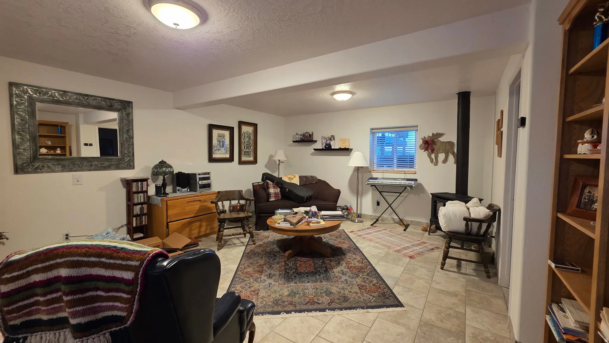Spacious room featuring tile flooring, a built-in wood-burning stove, and recessed lighting