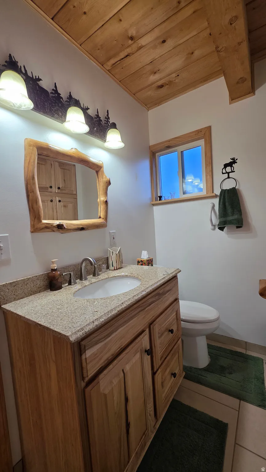 Bathroom featuring a wood-finish vanity with granite-style countertop and undermount sink