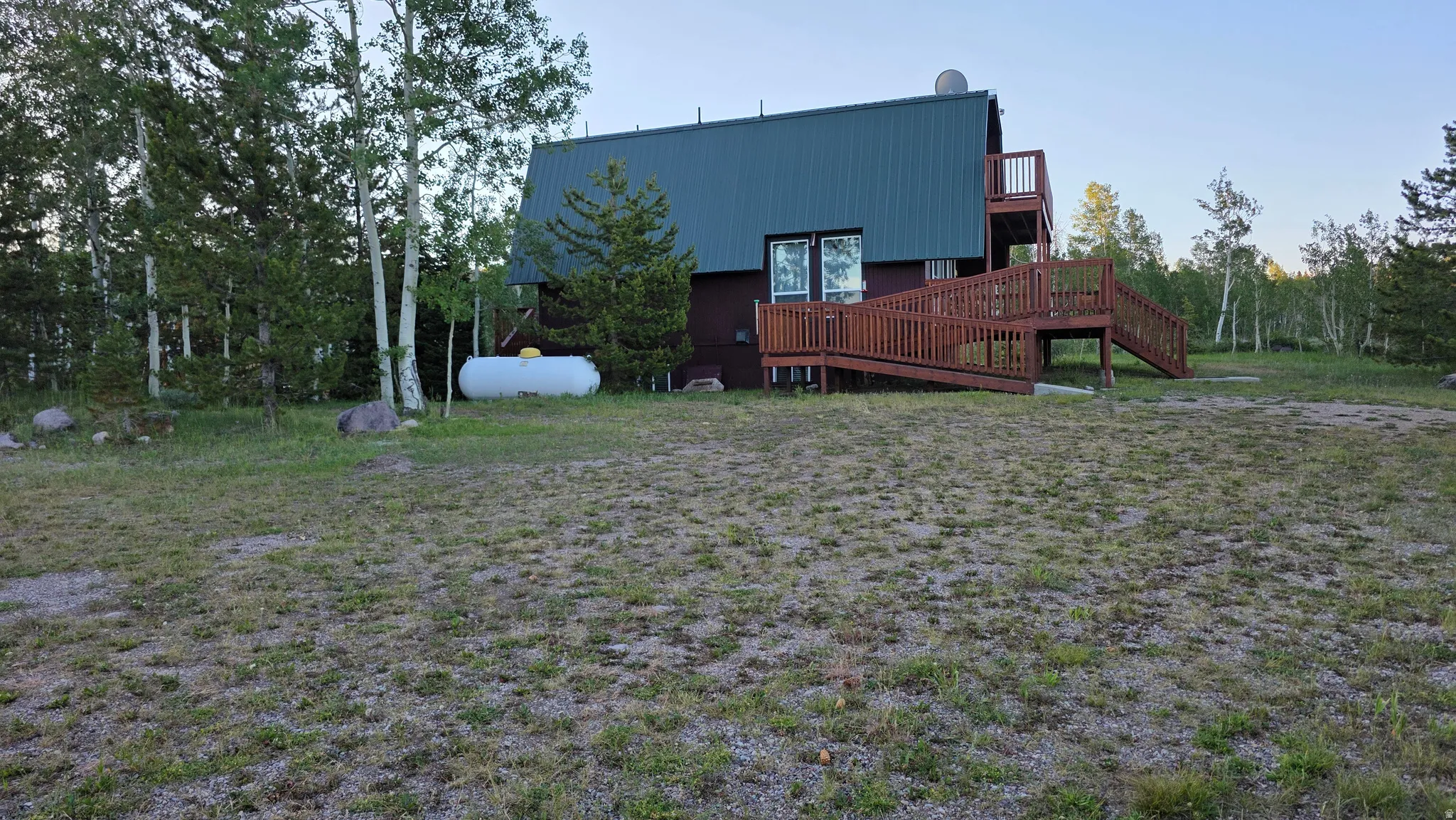 Wood-sided residence featuring a dark green metal roof and an extensive wood deck with an integrated ramp