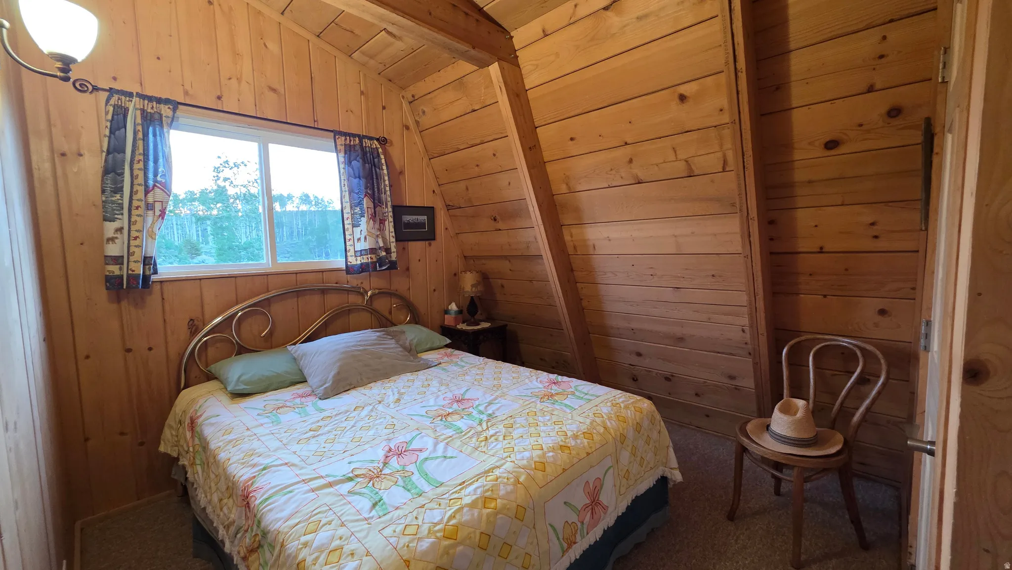 Interior room featuring natural wood paneling, a sloped ceiling, and a single window