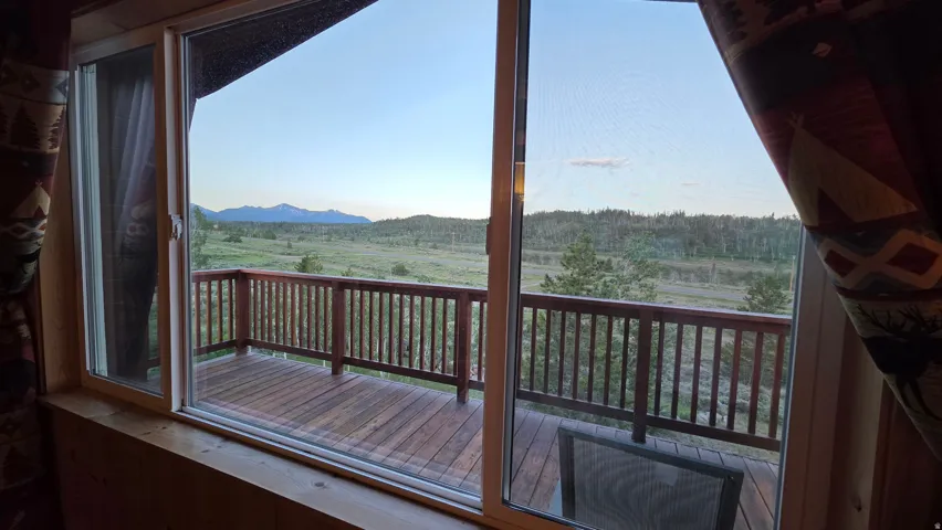 Sliding glass doors open to a spacious wooden deck with a spindle railing