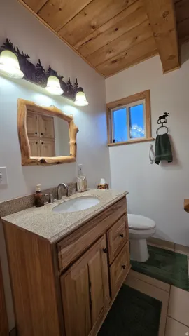 Bathroom featuring a wood-finish vanity with granite-style countertop and undermount sink