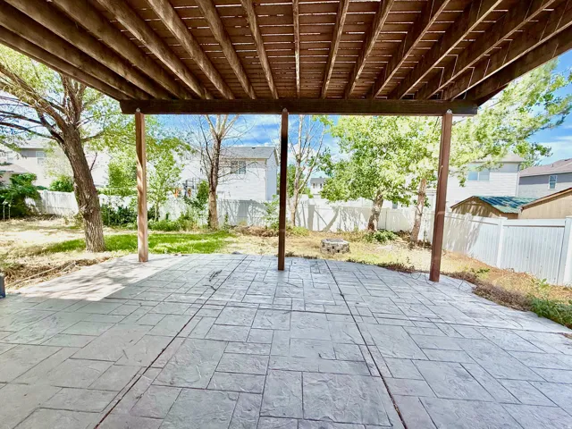 Covered patio featuring a stamped concrete surface, supported by exposed wood beams and posts