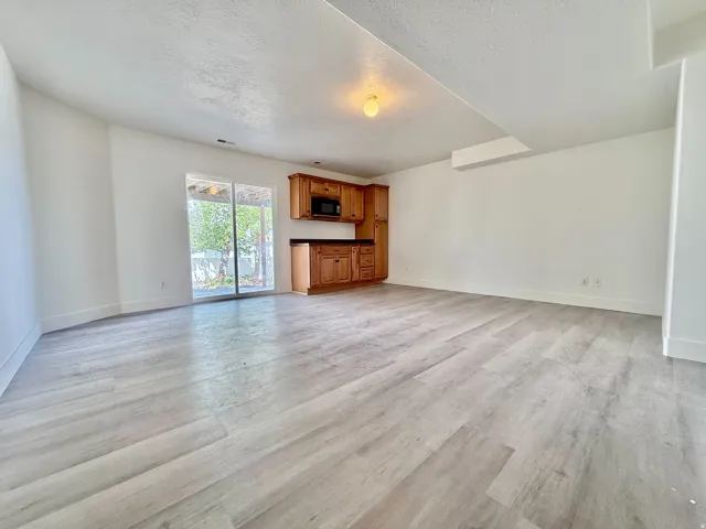 Spacious room featuring light wood-finish flooring, white walls, and a built-in kitchenette