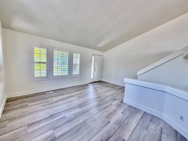 Spacious interior room featuring light wood-finish flooring, white walls, and bright white trim