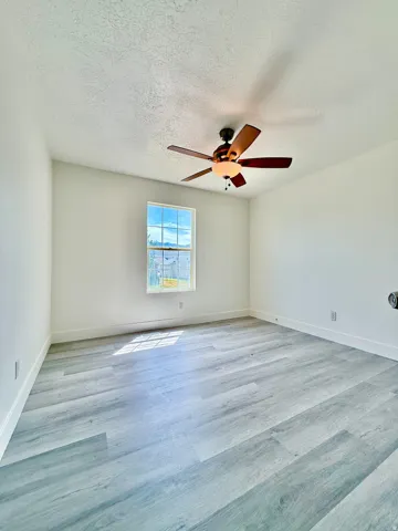 Light-filled room featuring wood-finish flooring, white baseboards, and a window providing natural illumination