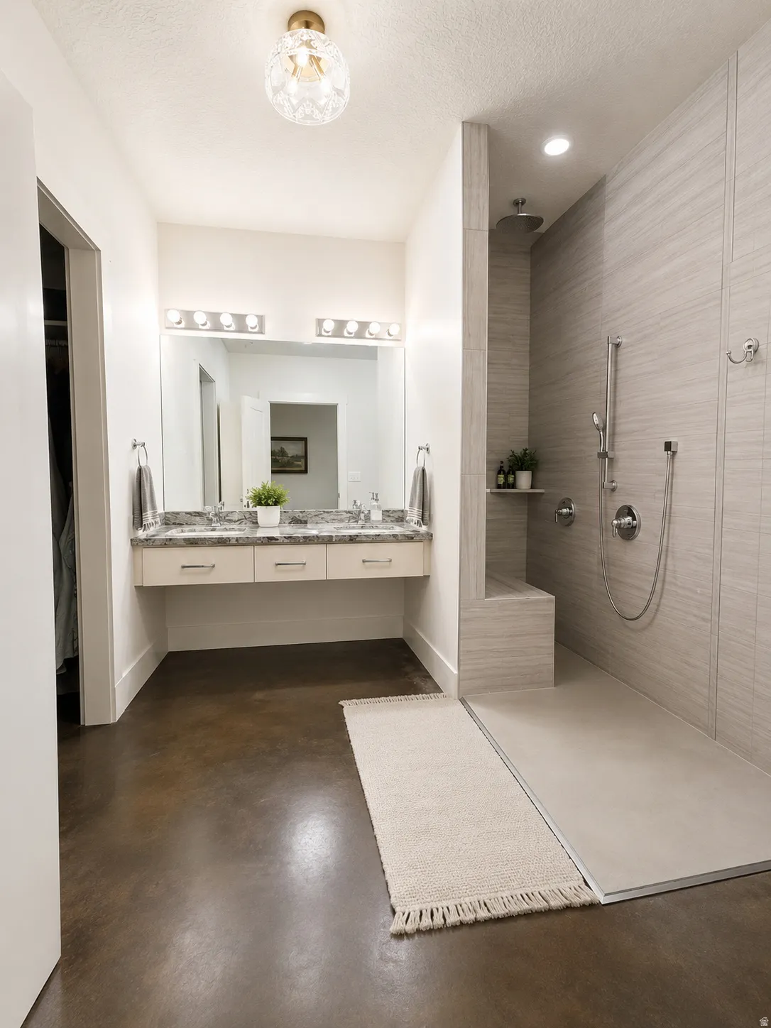 Spacious bathroom featuring a floating double vanity with a stone countertop, a large mirror, and a walk-in shower with a built-in bench