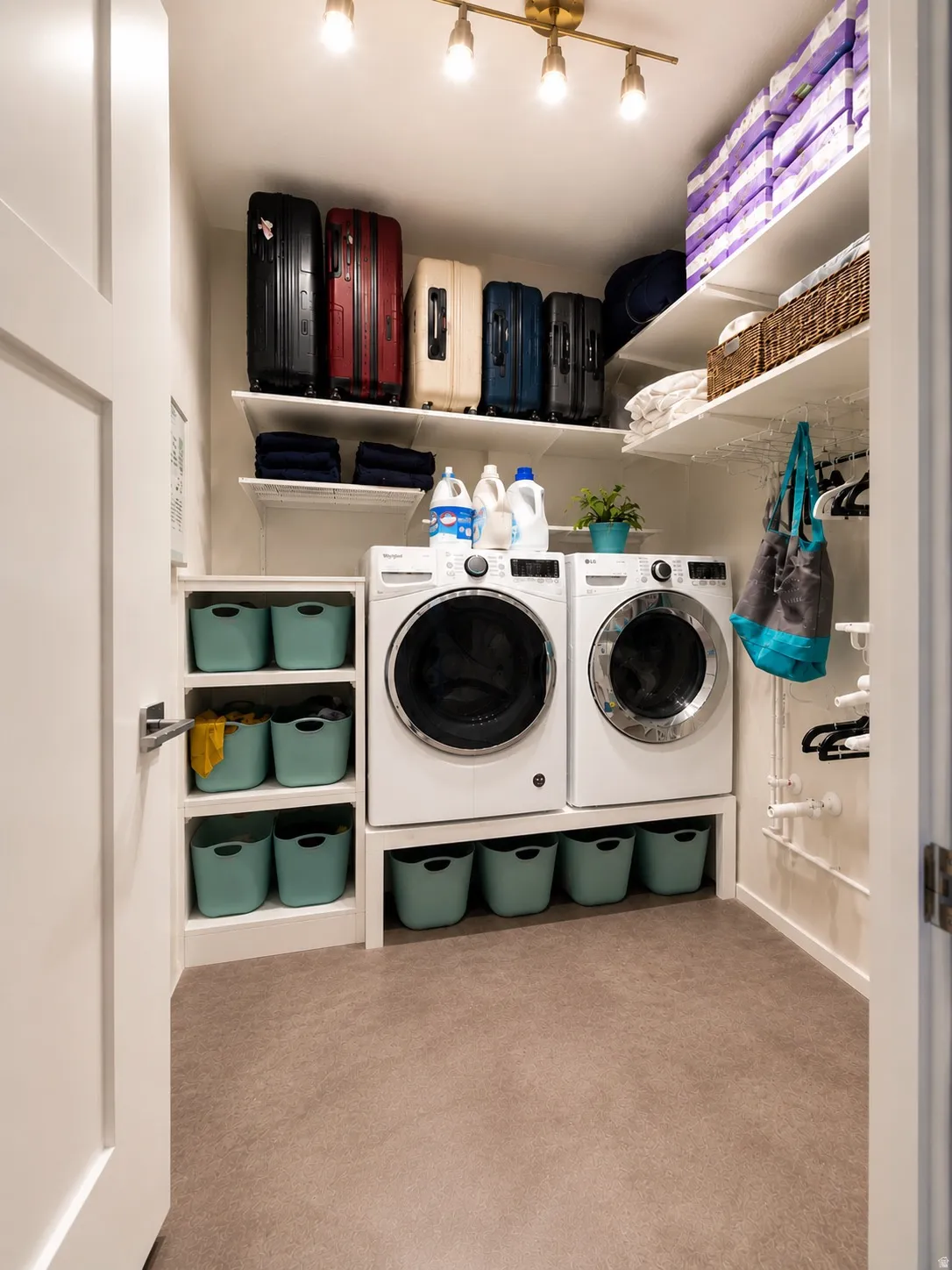 Dedicated laundry room featuring a front-loading washer and dryer, integrated shelving, and track lighting