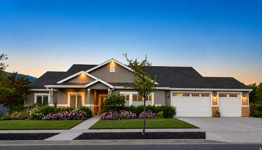 Exterior featuring a stucco finish, stone accents, and a dark shingle roof