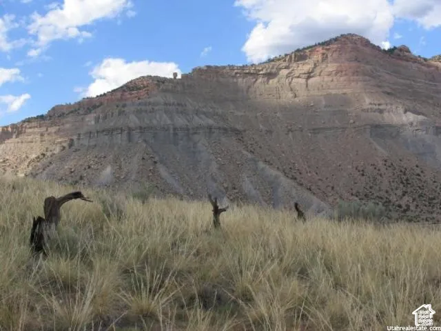 Expansive natural landscape featuring a prominent mountain backdrop with visible rock formations and arid vegetation
