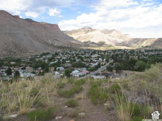 Expansive landscape featuring an elevated perspective of a town nestled within a mountainous terrain