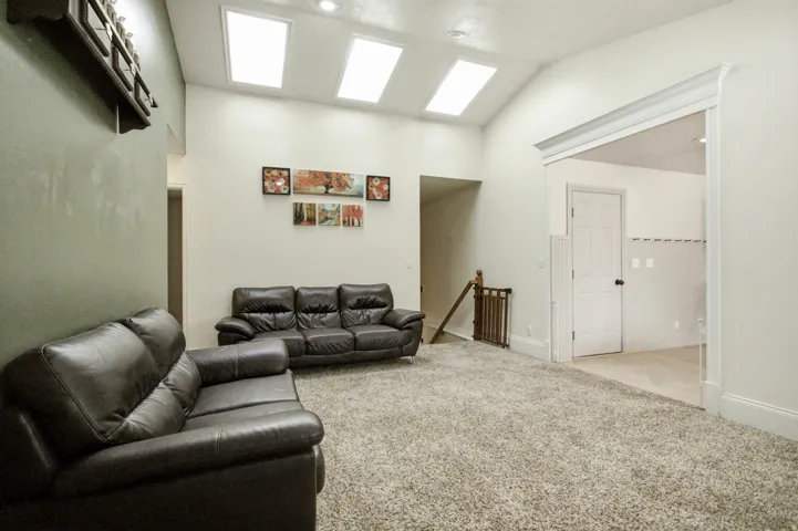 Spacious room featuring vaulted ceilings with multiple skylights and recessed lighting