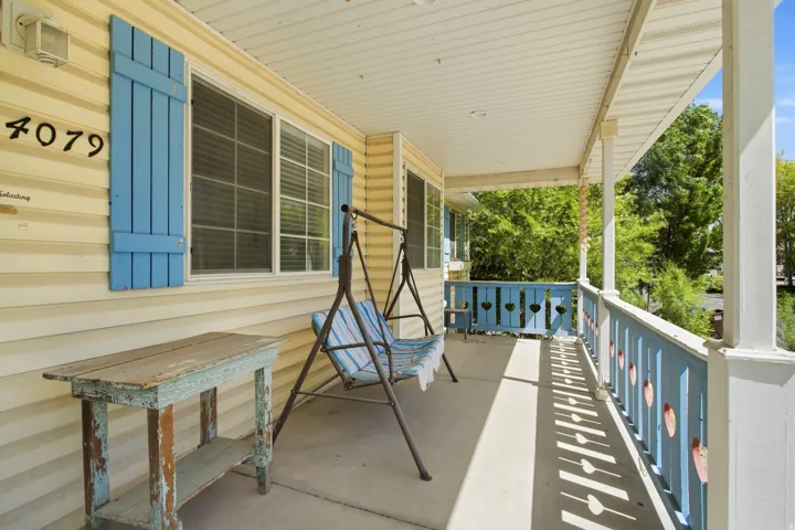 Inviting covered porch with light-colored siding, contrasting blue shutters, and a decorative railing featuring heart cutouts
