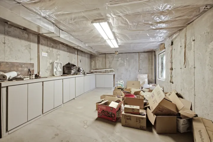 Basement space with concrete walls, exposed ductwork, and a window providing natural light