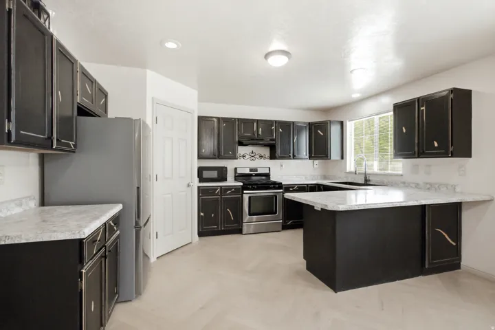 Kitchen featuring black cabinetry, light-toned countertops, and stainless steel appliances