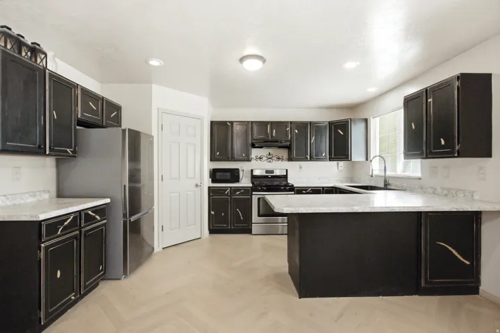 Kitchen featuring black cabinetry, light-toned countertops, and wood-finish flooring in a herringbone pattern