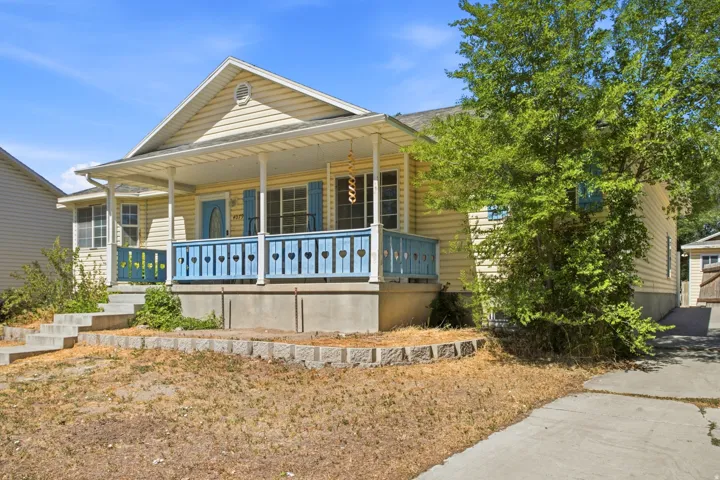 Light yellow siding exterior with a covered front porch featuring white columns and a blue railing