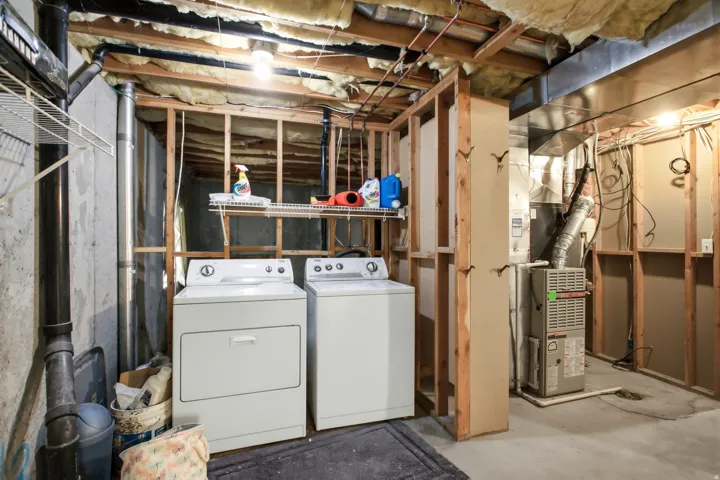 Unfinished basement featuring exposed wood framing, concrete flooring, and an installed furnace