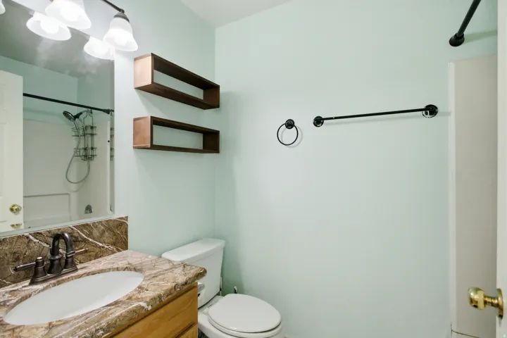Bathroom with a single vanity featuring a stone countertop, an undermount sink, and dark bronze fixtures