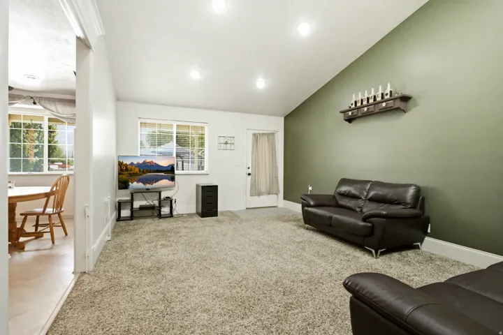 Carpeted living space featuring an angled ceiling, recessed lighting, and a contrasting accent wall