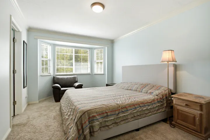 Carpeted room featuring a bay window, crown molding, and a flush-mount ceiling light