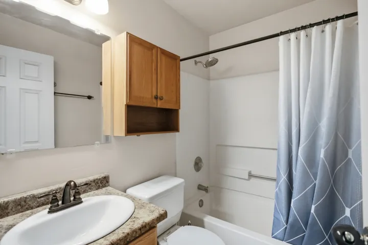 Bathroom featuring a vanity with an oval sink, speckled countertop, and wall-mounted mirror
