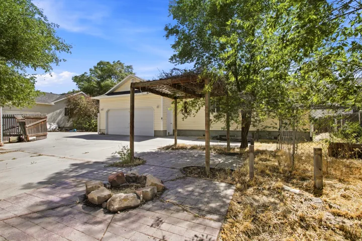 Paved patio area featuring a stone fire pit and an overhead pergola structure