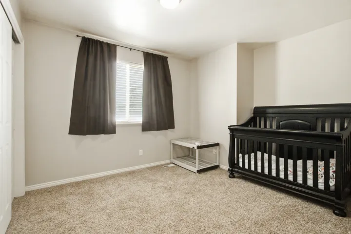 Carpeted room featuring a double-pane window with blinds, white trim, and a white bi-fold closet door