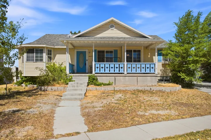 Front exterior featuring a covered porch with decorative railing, light-colored siding, and a vibrant blue front door