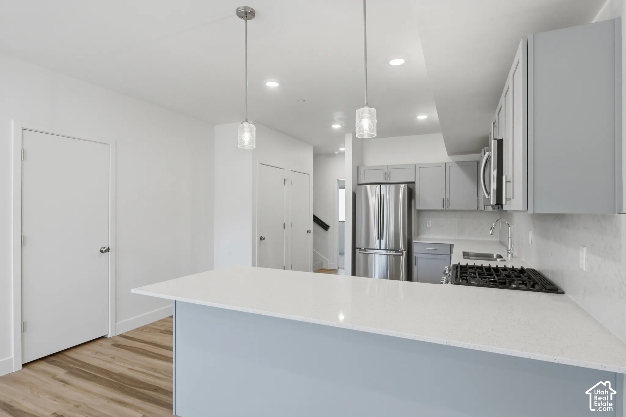 Kitchen bar seating with a white quartz countertop and two pendant lights