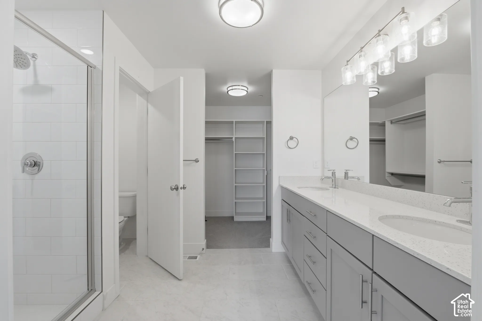 Primary ensuite bathroom with double vanity, grey cabinetry and white quartz countertops
