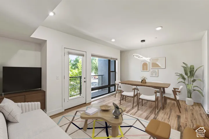 Open-concept living area featuring wood-finish flooring, recessed lighting, and a private balcony