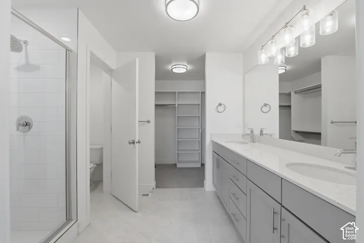 Primary ensuite bathroom with double vanity, grey cabinetry and white quartz countertops