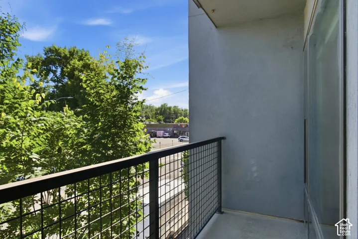 Private balcony with a metal grid railing and concrete flooring