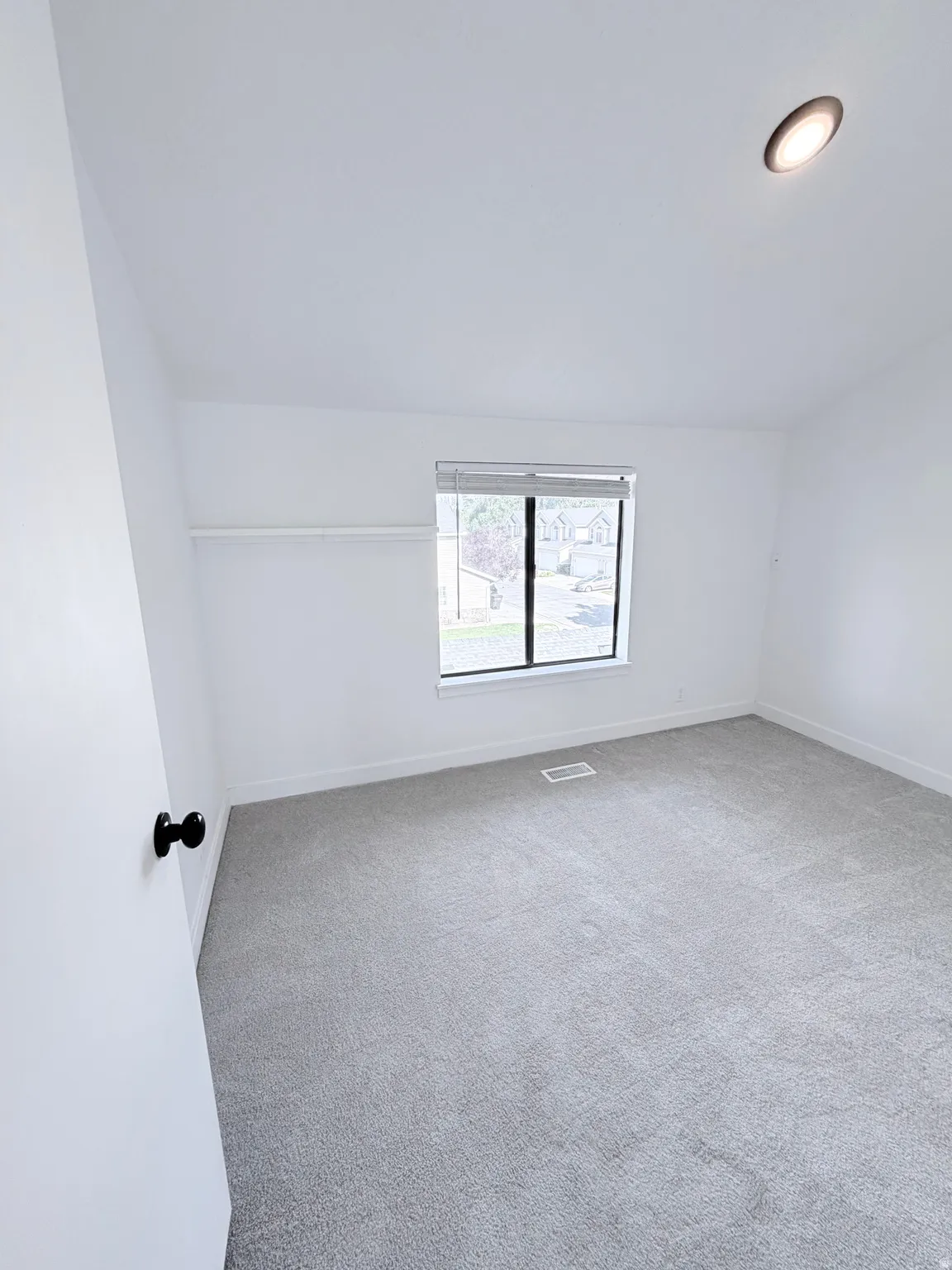 Carpeted interior space featuring a window with blinds, recessed ceiling lighting, and a closet with a shelf and hanging rod