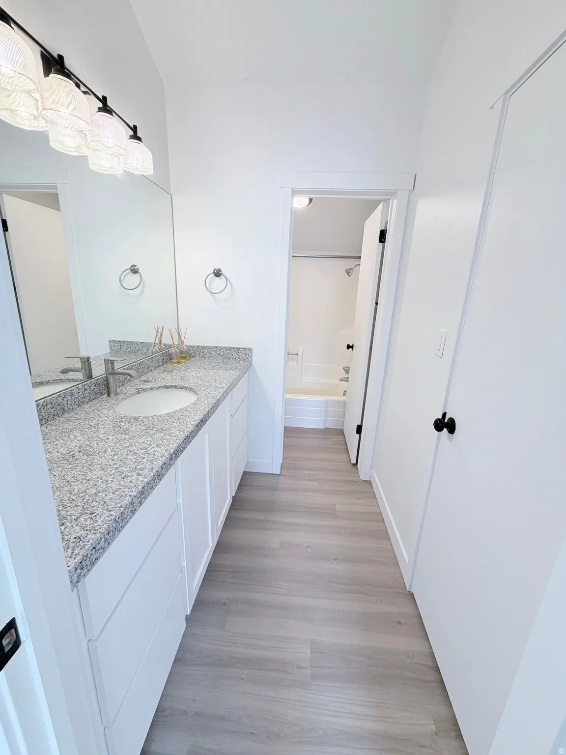 Bathroom featuring an extended vanity with a light-colored speckled countertop, undermount sink, and modern black hardware