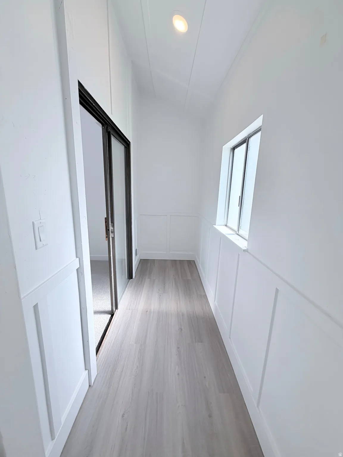 Hallway featuring wainscoting, wood-finish flooring, recessed lighting, and a sliding glass door