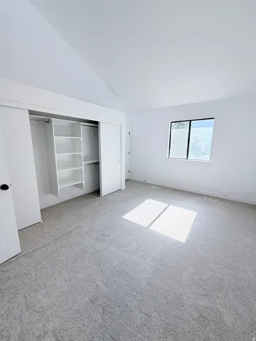 Interior room featuring a vaulted ceiling and light gray carpeting