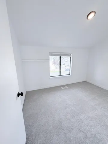 Carpeted interior space featuring a window with blinds, recessed ceiling lighting, and a closet with a shelf and hanging rod