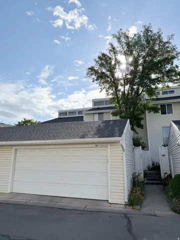 Double-car garage with a paneled white door, asphalt driveway, and light-colored siding
